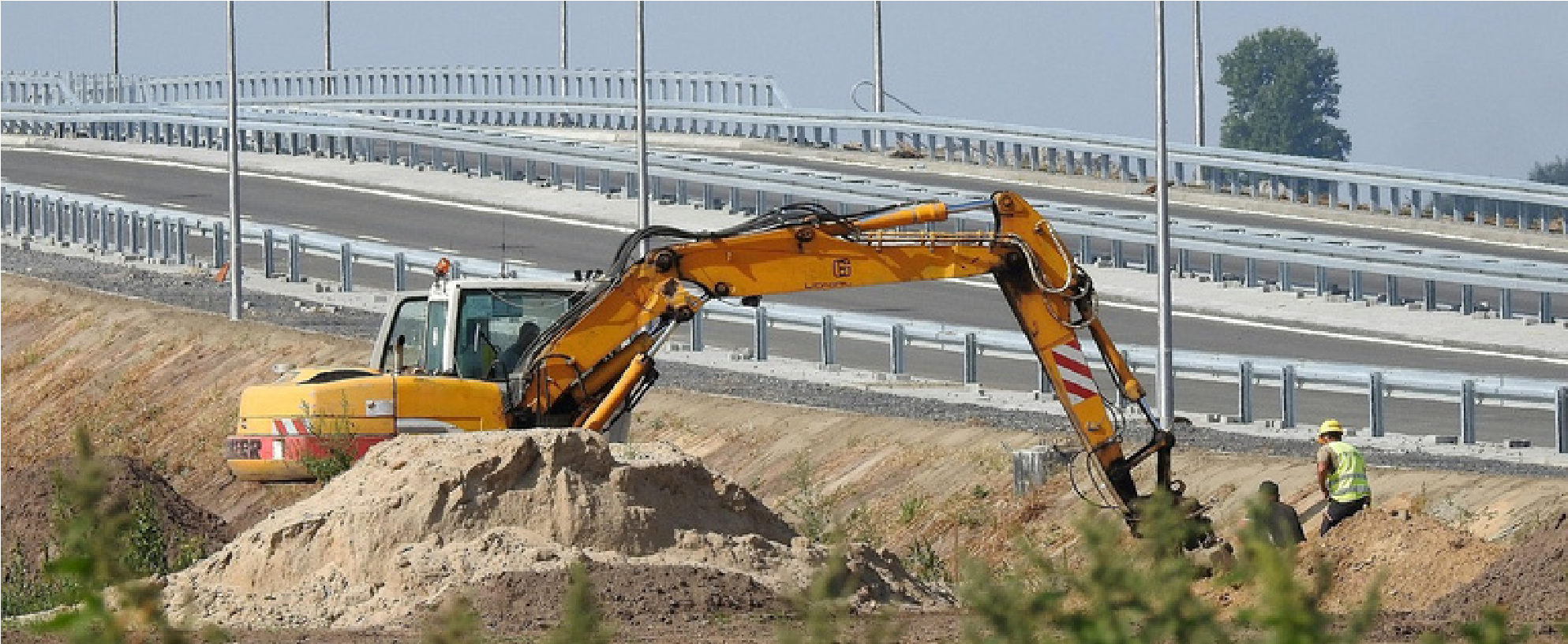 Construction equipment working alongside a completed roadway